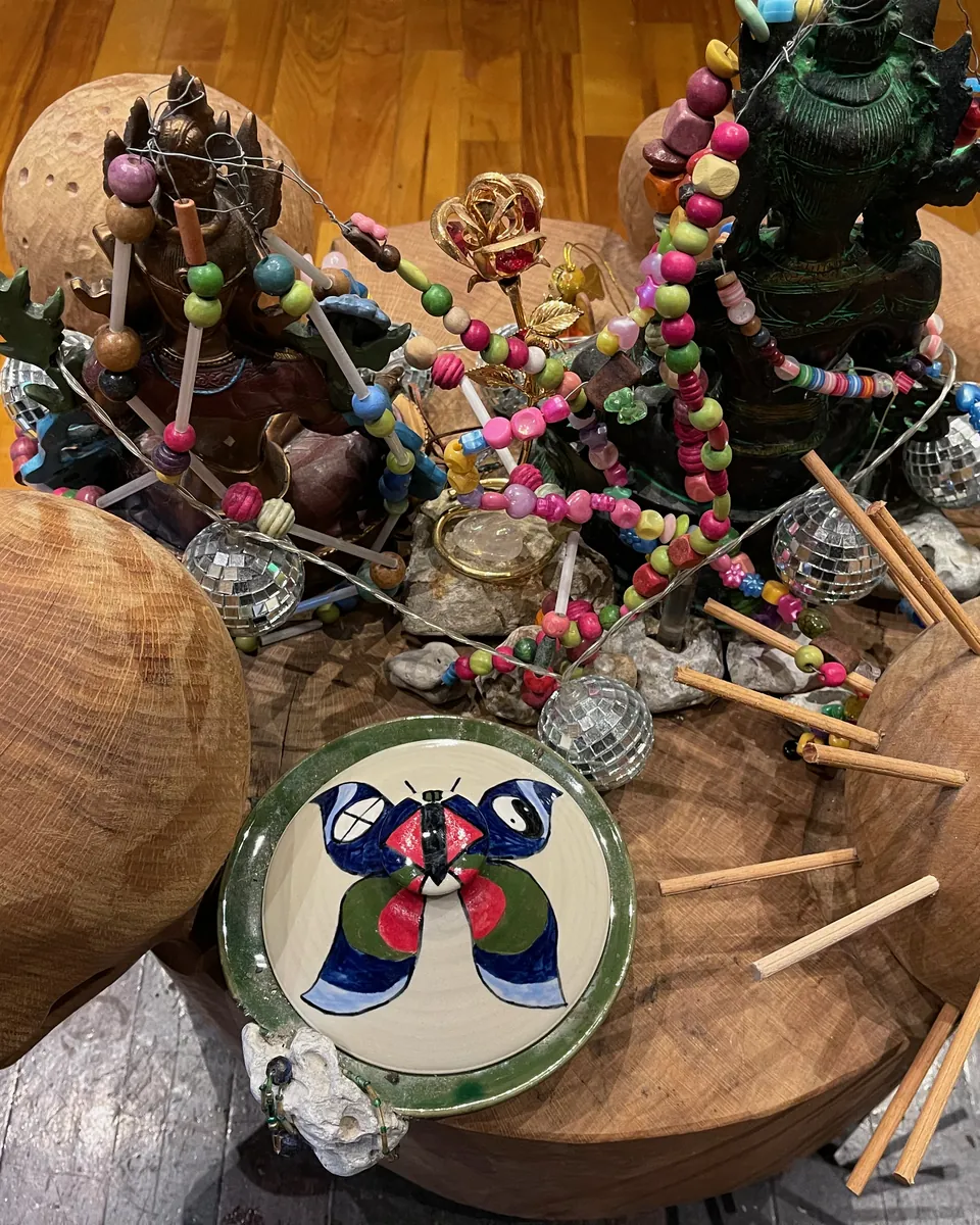 Alteret til en ayahuasca ceremoni i Rundsalen, set fra oven: trætromme, rasler, en tallerken med sommerfuglen, perlekæder og små figurer på trægulvet
