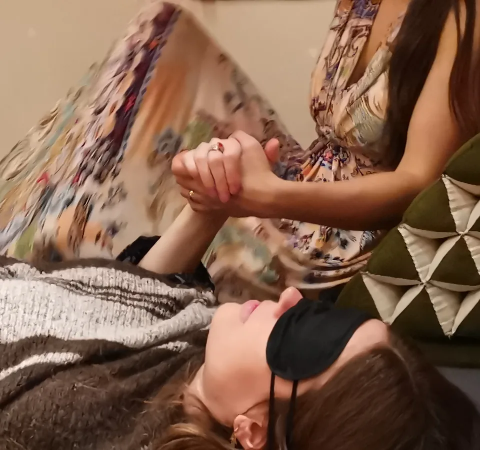 Ayahuasca-ceremoni: Ecaterina holder hænderne om en kvinde, der ligger med bind for øjnene under et tæppe.