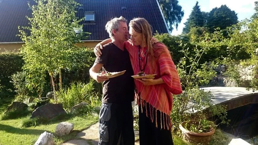 Jacob og Casper står tæt sammen i haven en sommerdag med hver sin tallerken mad – i haven er der ro til integrationen efter din ayahuasca ceremoni