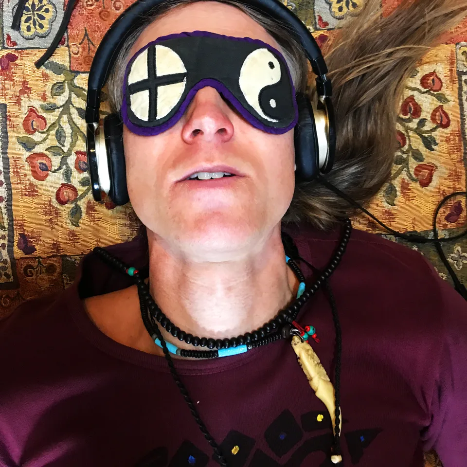 Jacob Moth ligger med øjenmaske og hovedtelefoner på en af sine egne indre rejser, set tæt på ovenfra – han guider selv individuelle ayahuasca ceremonier og kender vejen indefra