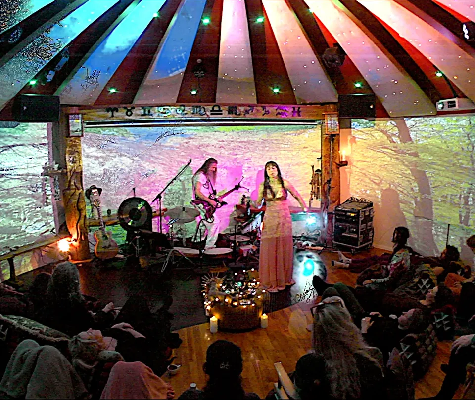 Ecaterina and Jacob Moth playing at the full moon concert in the Roundhall in April 2024; the guests sit and lie on cushions on the floor in front of them