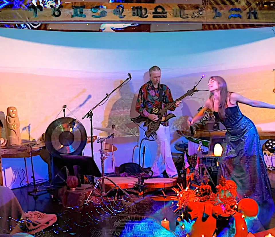 Jacob and Ecaterina Moth playing in the Roundhall at the full moon concert in January 2026: Jacob with a butterfly guitar, Ecaterina with her arms spread wide, in front of a gong and drums